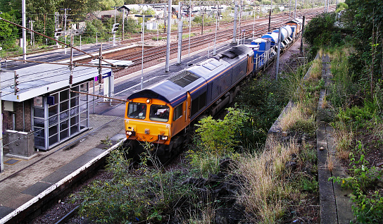 A diesel freightliner locomotive is pulling a goods / freight train at Alexandra palace station London  England UK. It is a sunny day in Spring and there are no people in the picture.