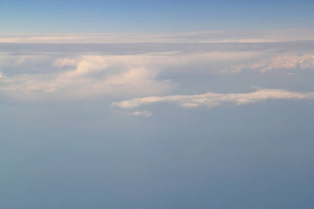 This serene photograph captures the tranquil beauty of a sunrise over a sea of clouds. The soft, fluffy formations stretch endlessly, bathed in the gentle hues of early morning light. A moment of peace and reflection, inviting viewers to appreciate the wonders of nature from an elevated perspective.