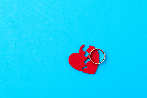Wedding ring with broken heart on blue background