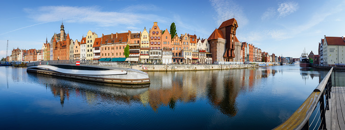 Gdansk, Poland - July 15, 2023: Panorama of the facades of old medieval colorful houses on the promenade in Gdansk. Beautiful morning scenery of Motlawa River embankmentwith reflection in water. City center of Gdansk