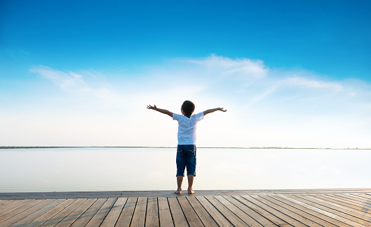 Little boy standing on the beach with arms outstretched