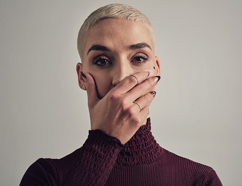 Woman, fear and hand cover mouth for studio portrait with silence, anxiety and mental health by white background. Girl, person and quiet for stress, depression or abuse in shock, secret and scared