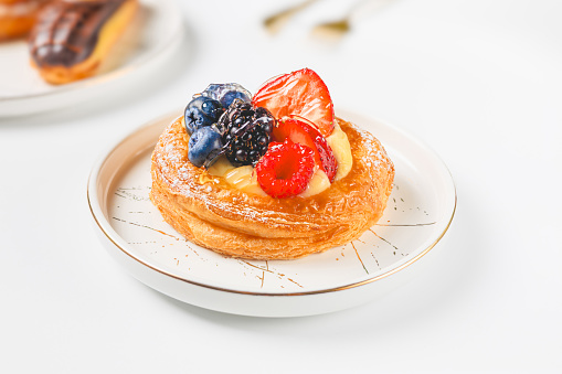 Delicious puff pastry with cream and berries on a white plate.