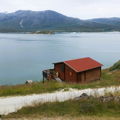 A wooden dwelling situated in a secluded coastal area in Greenland, captured on August 20, 2023, in the western part of the region.