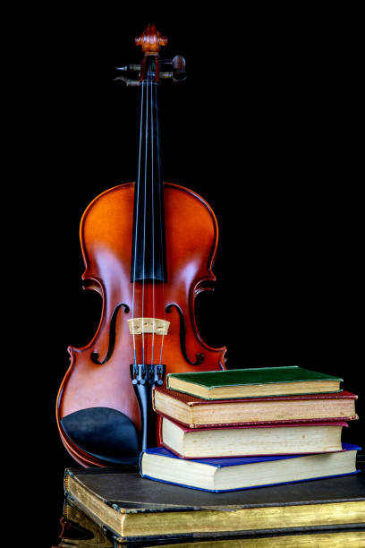 istock Violin with Old Books on a Reflective Black Surface and Black Background 1972581165