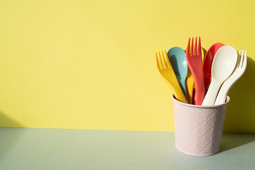 Kitchen utensil. Cutlery spoon fork in holder on gray table. yellow wall background