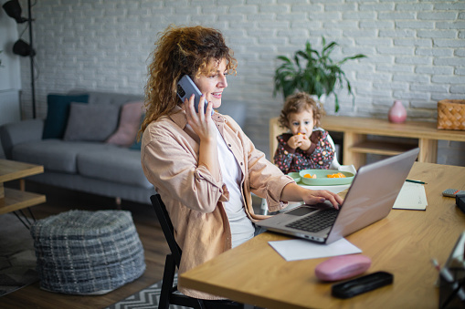 Young mother working from home while taking care of her baby