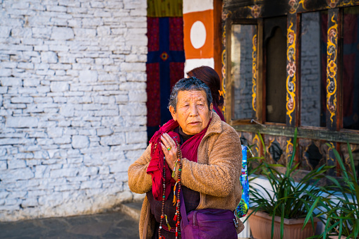 Thimphu, Bhutan - 30th December 2023. A old wome with hands folded prayig in a temple coumpound in Bhutan