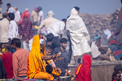 Varanasi, Uttar Pradesh, India - March 2023: Masan holi, unidentified sadhu baba sitting at manikarnika ghat during masan holi festival.