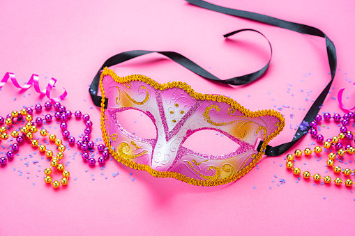 Pink Mardi Grass mask on pink background. Copy space. High resolution 42Mp studio digital capture taken with Sony A7rII and Sony FE 90mm f2.8 macro G OSS lens