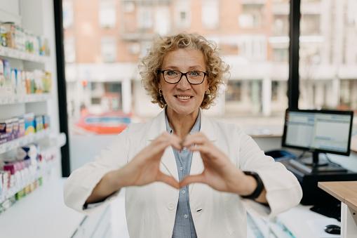 Female pharmacist holding heart shape using left and right hand