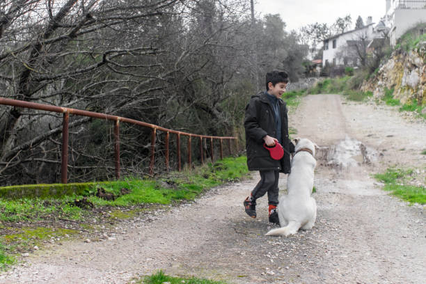 View of a happy child walking with dog in dirt road.