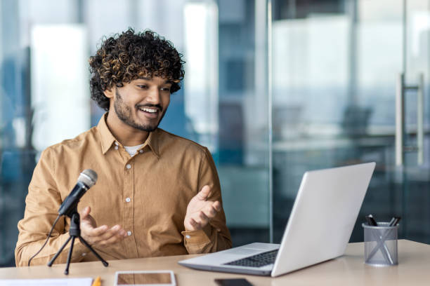 istock Confident young businessman speaking into microphone during webinar 1972663884