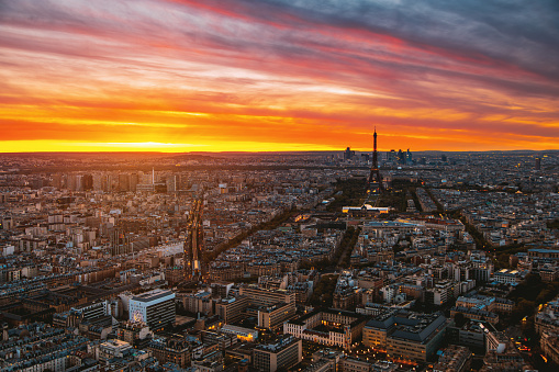 A cityscape view of golden sun sets behind the enchanting city of Paris, the aerial view captures the breathtaking beauty of the iconic Eiffel Tower, standing tall amidst the stunning architecture and charming neighborhoods, casting a warm and inviting glow on the entire Paris city, lle de France