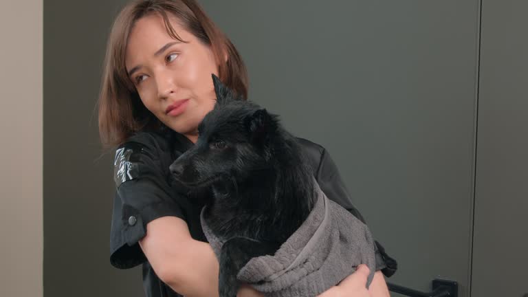 beautiful kind woman kissing, hugging her dog after washing at pet salon