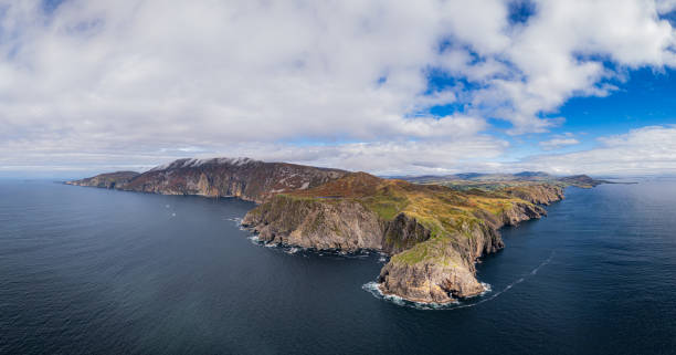 Aerial view of rugged coastal cliffs and clear blue sea in a scenic landscape.