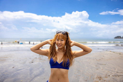 Portrait of woman in bikini standing at summer beach