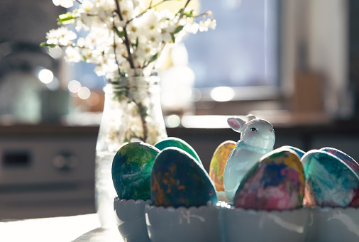 Table with easter egg for breakfast and easter bunny with sunlight in springtime. Decorating eggs.