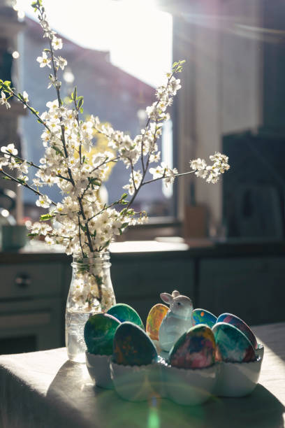 Table with easter egg for breakfast and easter bunny with sunlight in springtime. Decorating eggs.