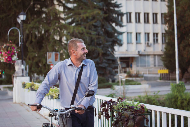 Happy businessman going to work by retro bike. 15 minute cities concept. Sustainable living. Active urban lifestyle.
