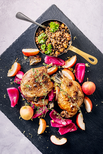 Duck confit with pigeon apples, picked red onions, figs and puy lentils. Overhead view, colour, vertical format with some copy space.