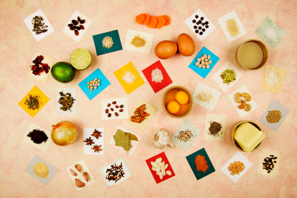 Overhead view of food ingredients over colored  labels .  The food ingredients are: brown rice, white rice, rolled oats, yellow peas, chickpeas, split peas, salt, shredded coconut, chocolate chips, sesame, slivered almonds, cashew, chia, quinoa, coffee beans, raisins, whole wheat, cinnamon stick hibiscus flower, green tea, star anise, cloves, ground coffee, black peppercorns, oregano, garlic cloves, wheat flour, garlic powder, brown sugar, birdseed, bay leaves, sunflower seeds,onion,butter,cooking oil,lemon and two yolk eggs in small bowl. Image made in studio