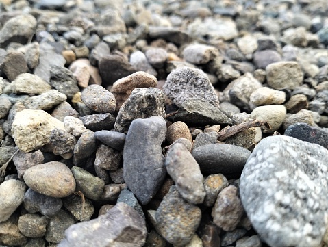 Mound of granite gravel, stones, crushed stone close-up. Rough seamless texture, construction material background.