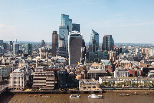 The sun bathes London's Financial District in a warm glow as the city's iconic skyline emerges in a symphony of architectural marvels. This aerial view from the south showcases the dynamic energy of the downtown district, where modern skyscrapers and historic landmarks coexist, defining the heartbeat of England's vibrant capital city