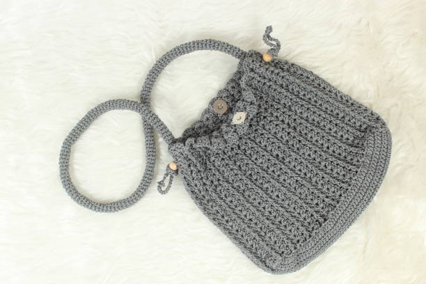 istock Knitted handmade gray bag on furry white blanket. Top view. 1972733205