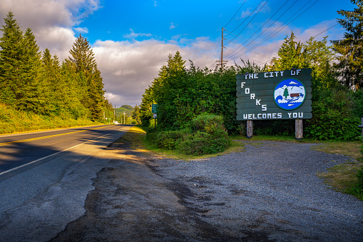 Forks, Washington, USA - June 11, 2023: Welcome sign for the City of Forks, surrounded by dense forest of Olympic Peninsula