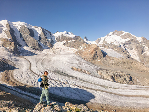 Male hiker looks out at view above glacier