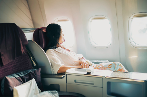 A relaxed business class passenger is looking out of the window of a passenger aircraft.