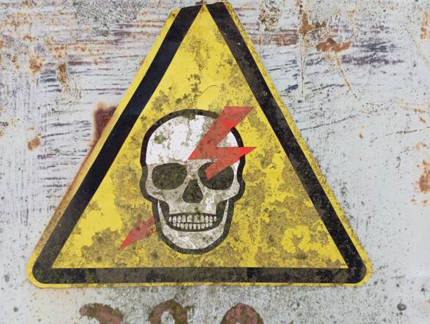 istock A yellow triangular sign with a skull pierced by lightning. A high voltage warning sign is applied to the gray surface of the switchboard. 1972752434