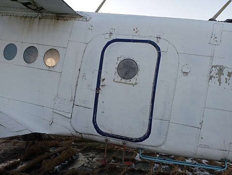 Part of a small single-engine aircraft with round doors and portholes. Entrance to the plane from the side.
