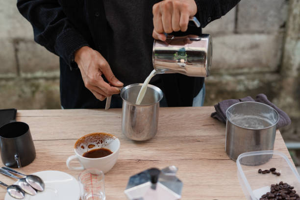 istock preparing to make coffee, person hand using a Pitcher makes latte coffee with equipment tool brewing table. 1972761264
