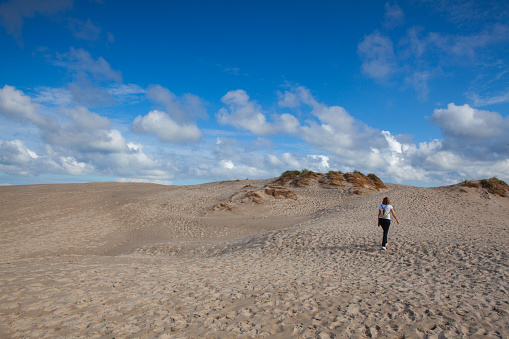 Skagen,Denmark - 14 August 2018: Lonely woman on the Rabjerg Mile. It is a migrating coastal dune between Skagen and Frederikshavn. It is the largest moving dune in Northern Europe with an area of around 2 km and a height of 40 m above sea level.