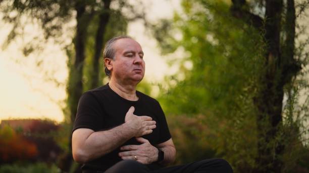 istock Senior man practicing yoga and doing breathing exercise and meditating in nature 1972778706