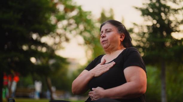 Senior woman practicing yoga and doing breathing exercise and meditating in nature