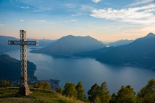 Cross on top of a mountain with lake and sky on the background