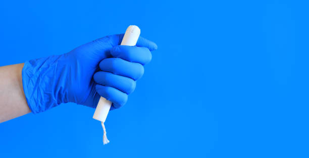 tampon in a cardboard applicator in a woman's hand, blue background - tampon menstruation applicator hygiene fotografías e imágenes de stock