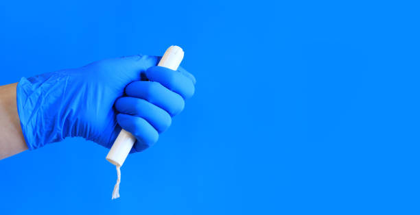 tampon in a cardboard applicator in a woman's hand, blue background - tampon menstruation applicator hygiene fotografías e imágenes de stock