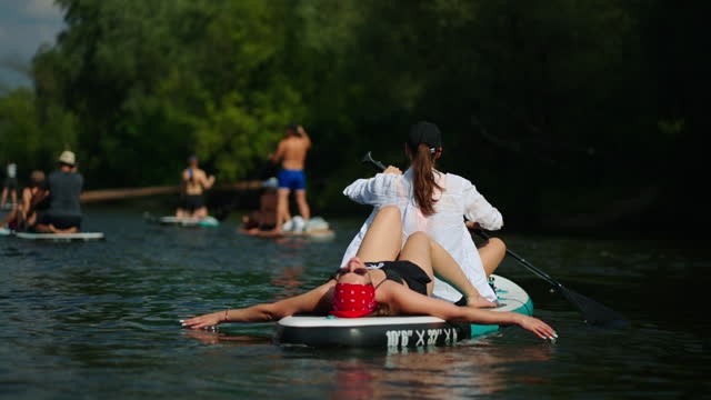 People Resting And Relaxing In Nature, Practicing Standup Paddleboarding In River In Summer