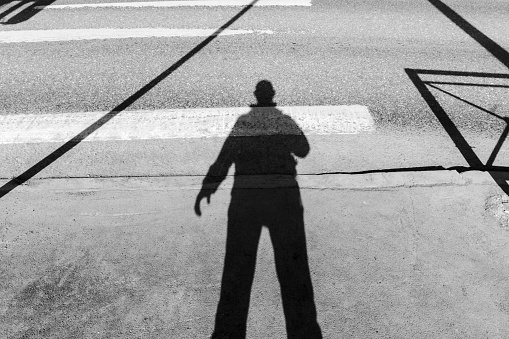 Shadowy Figure Strolling Down an Urban Street. Black and white photo. Selective focus
