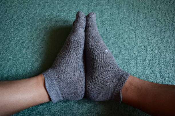 Figure of human feet wearing grey socks performing yoga