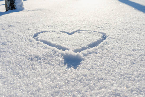 istock One hand drawn heart shape in the fresh snow.Top view,closeup,copy space. 1972832539