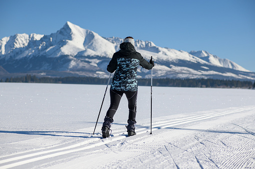 young woman cross country skiing on a snowy meadow with a view of the High Tatras-Krivá.