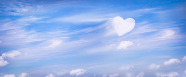 Fluffy clouds forming a heart shape on blue sky background, soft focus. Heavenly clouds. Holidays of love, Valentine, Mother day, romantic. Copy space. Empty place for message.