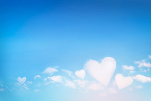 Fluffy clouds forming a hearts shape on blue sky background, soft focus. Heavenly clouds. Holidays of love, Valentine, Mother day, romantic. Copy space. Empty place for message.