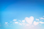 Fluffy clouds forming a hearts shape on blue sky background, soft focus.