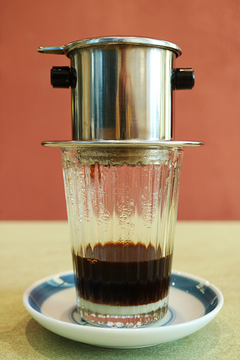 Closeup of Vietnamese Drip Coffee Slowly trickling Into Transparent Glass with Condensed Milk